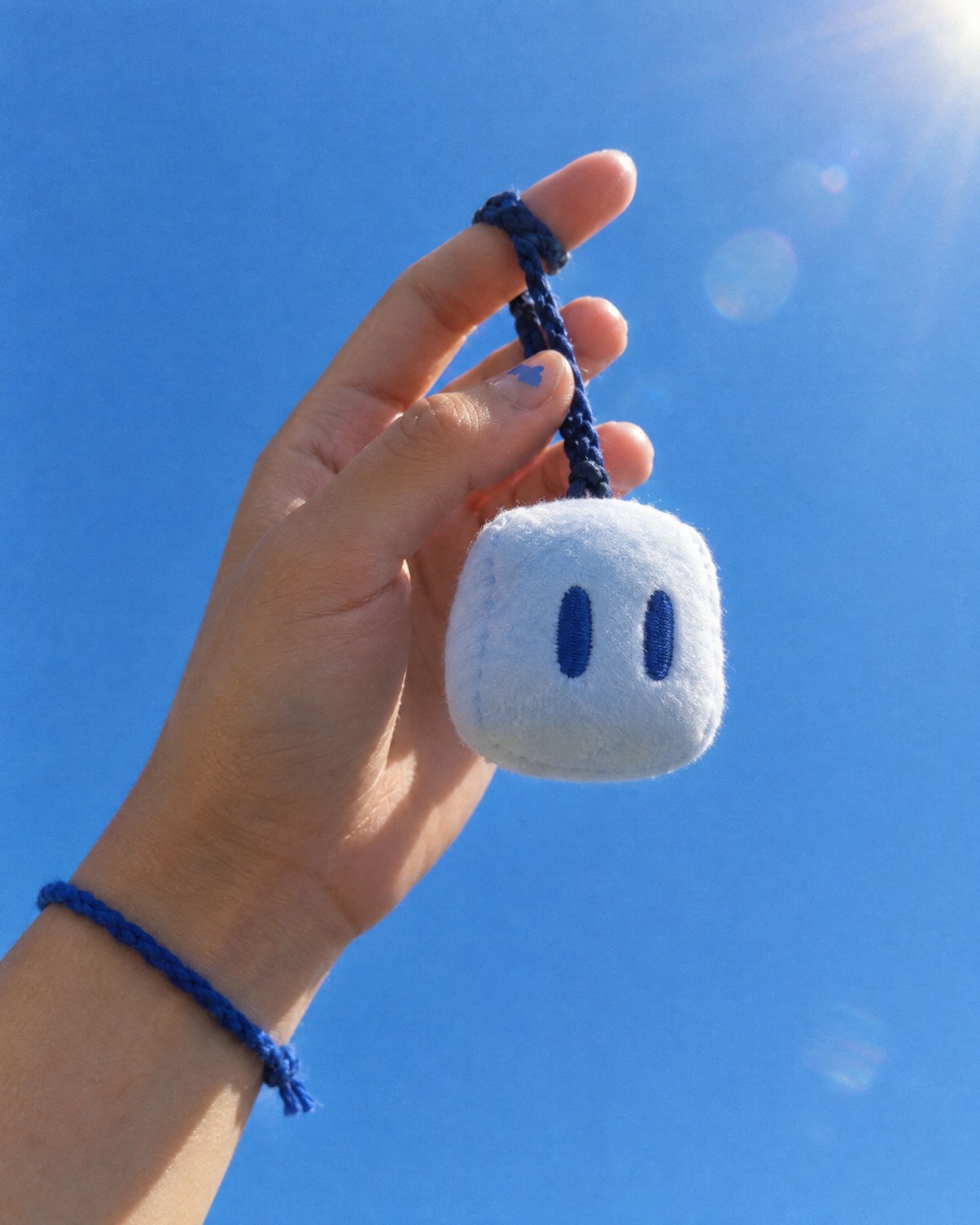 A hand holding a small Pip charm up against a blue sky